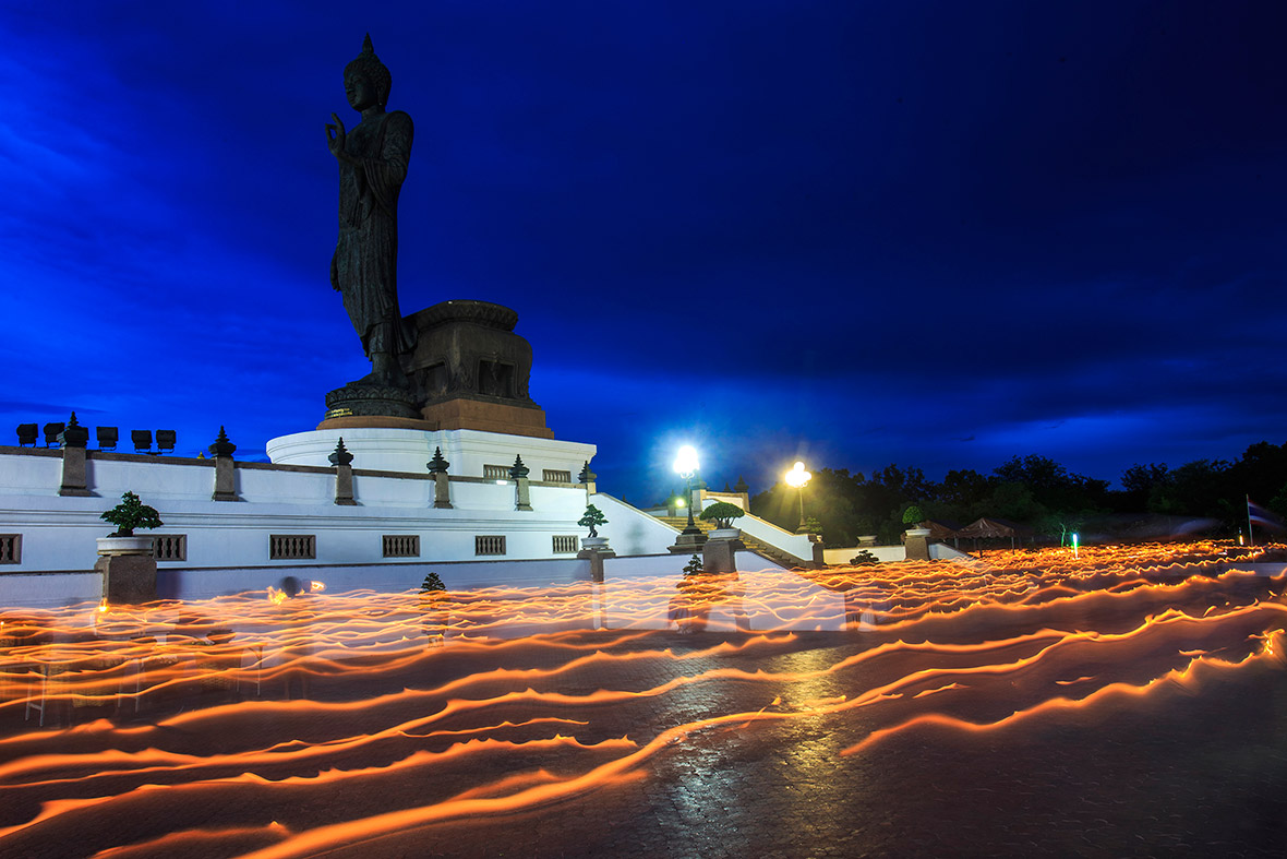 Buddhists holding candles leave a light trail as they walk around a large Buddha statue during Vesak Day, an annual celebration of Buddha's birth, enlightenment and death, at a temple in Nakhon Pathom province on the outskirts of Bangkok