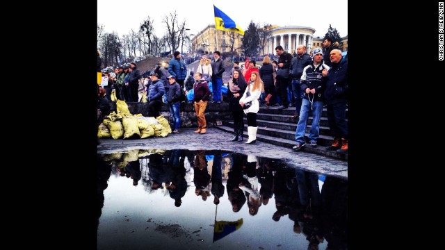 KIEV, UKRAINE: Ukrainians are reflected in a puddle as they gather to mourn the dead in Maidan Square on February 23, after protesters succeeded in forcing President Viktor Yanukovich out of office. Photo by CNN's Christian Streib. Follow Christian on Instagram at http://ift.tt/1oUPDqV.