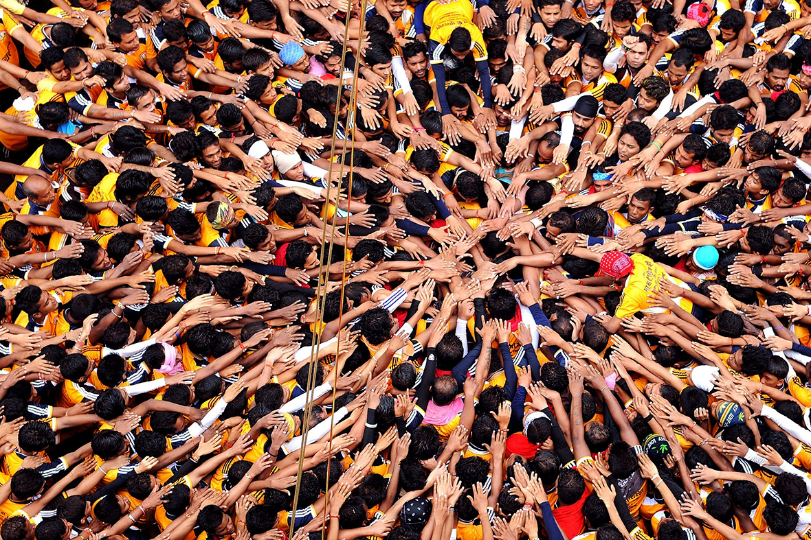 Indian Hindu devotees reach out before attempting to form a human pyramid in a bid to reach and break a dahi-handi (curd pot) suspended over the crowd during celebrations for the Janmashtami festival, marking the birth of Lord Krishna, in Mumbai