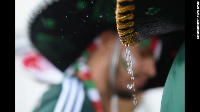 Rain drips off a Mexico fan's sombrero before the match. 