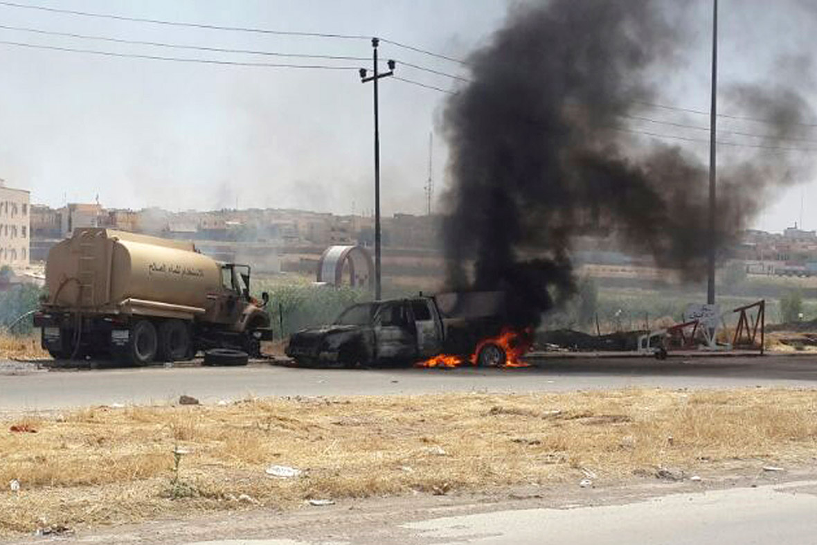 Burning Iraqi security force vehicles are seen during clashes in the northern Iraq city of Mosul.