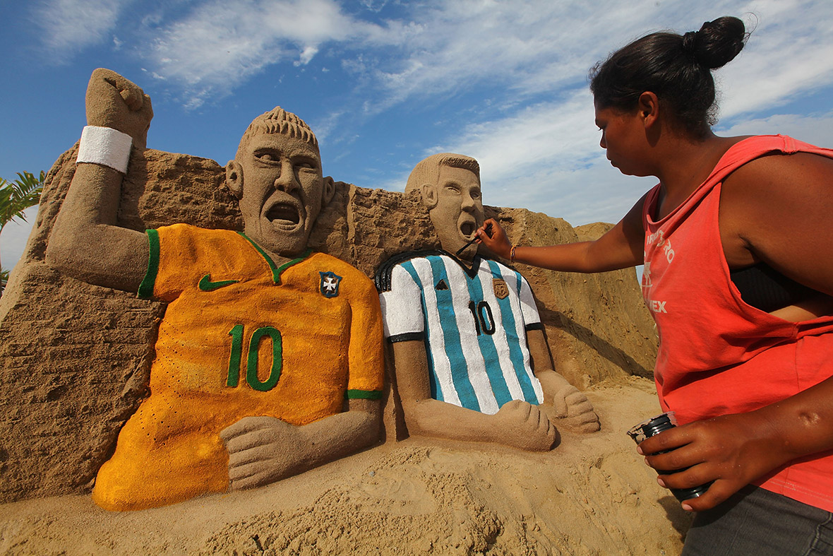 An artist paints a sand sculpture of Neymar and Messi on Copacabana Beach in Rio de Janeiro, Brazil