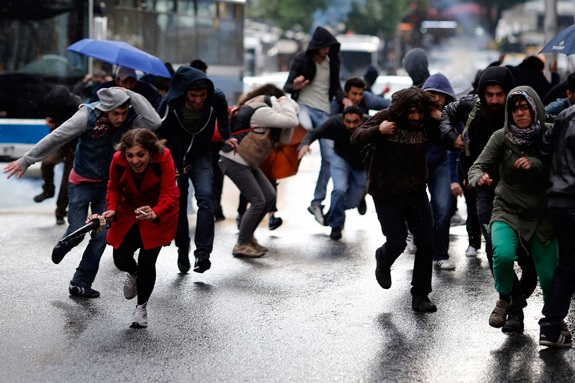 People run away as tear gas is fired during clashes between riot police and demonstrators in Ankara, Turkey