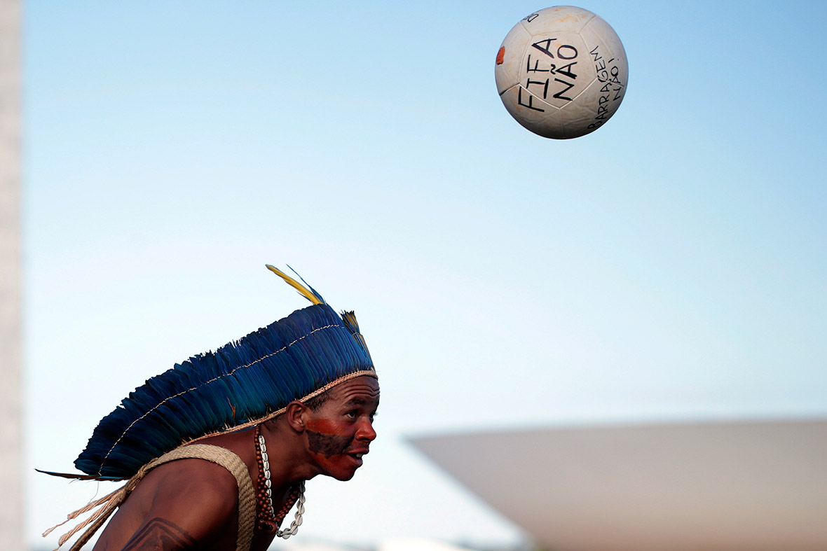 An indigenous Brazilian man heads a football during a protest against the policies of President Dilma Rousseff's government and the costs of the 2014 World Cup in front of the Brazilian congress in Brasilia