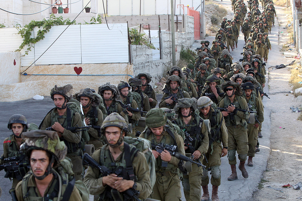 Israeli soldiers walk in lines during an operation in the West Bank town of Hebron during the search for three teenagers believed to have been kidnapped by Hamas militants