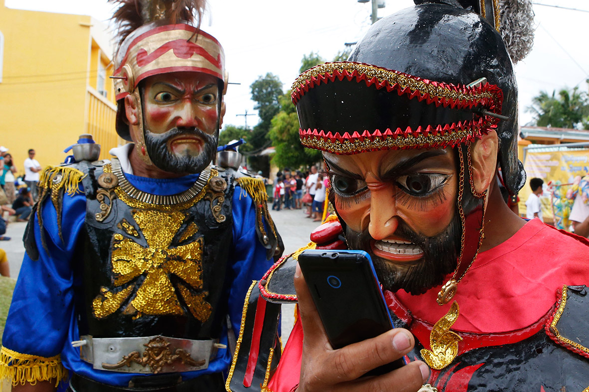A masked penitent dressed as a Roman soldier checks his mobile phone during Holy Week on Marinduque island in the Philippines