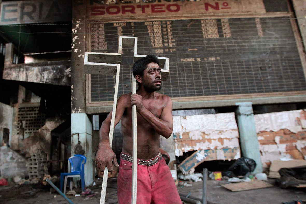 A resident of a building damaged by a previous earthquake in 1972 carries a cross as he leaves the building after another earthquake shook Managua, Nicaragua