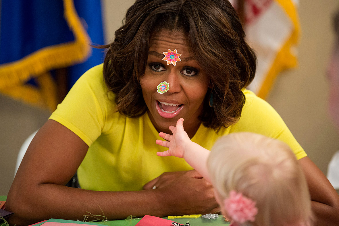 US first lady Michelle Obama has stickers put on her face by 20-month-old Lily Oppelt during a visit to the Fisher House at Walter Reed National Military Medical Centre in Bethesda, Maryland
