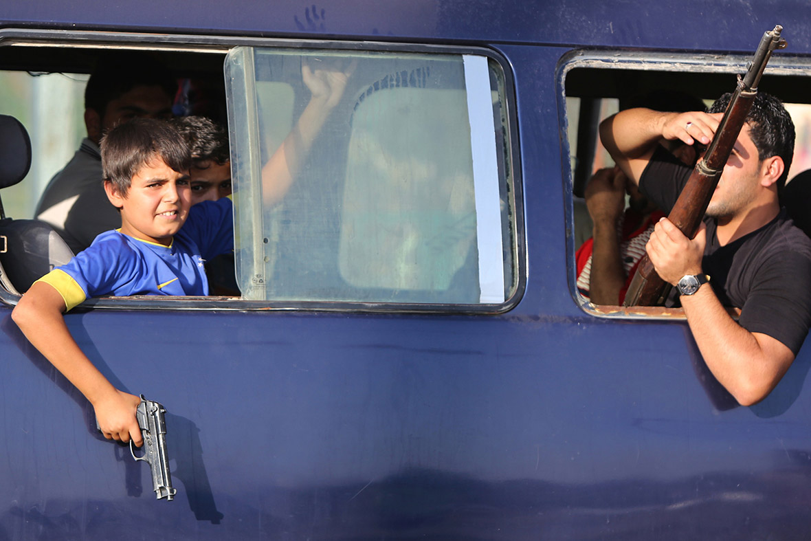 An young boy holds a gun at the window of a vehicle carrying volunteers in Baghdad.