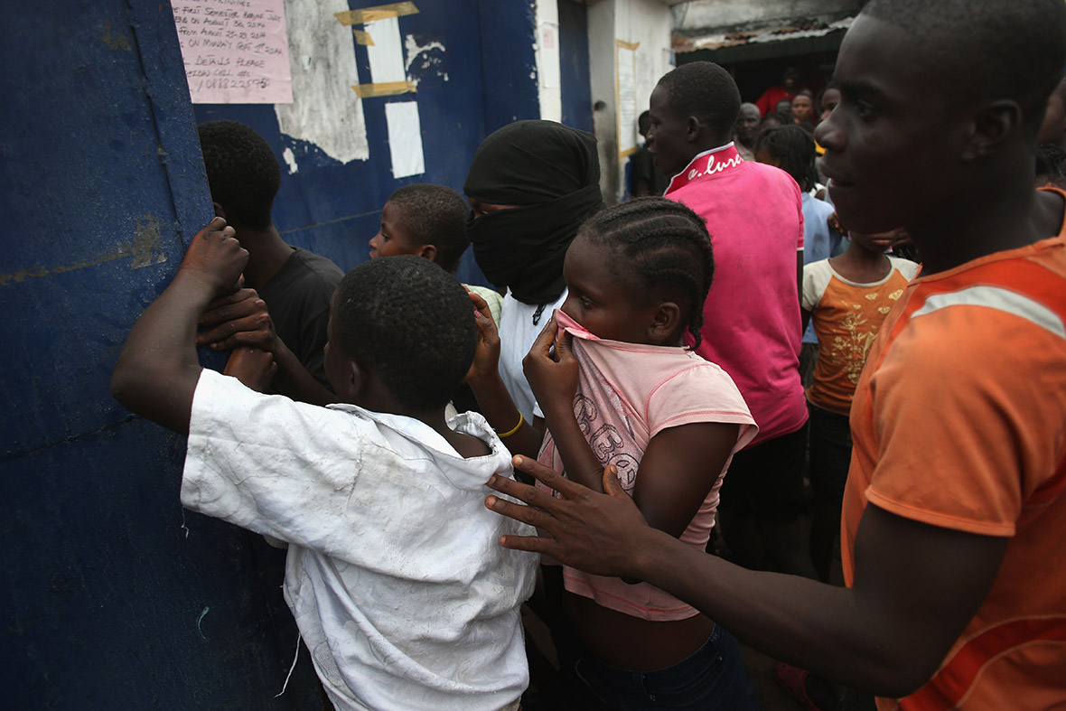 A crowd forces open the gates of an Ebola isolation centre in the West Point slum