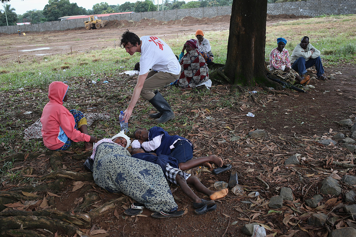 Doctors Without Borders (MSF), staff member Brett Adamson hands out water to sick Liberians hoping to enter the new MSF Ebola treatment centre near Monrovia
