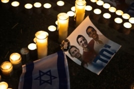 Candles placed next to a picture of three Israeli teenagers who were abducted and killed, in Tel Aviv's Rabin Square, June 30, 2014.
