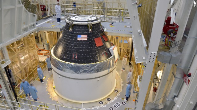 NASA's first completed Orion crew module sits atop its service module at Kennedy Space Center before being wrapped in protective panels and stacked on a Delta IV Heavy rocket for its first test flight.
