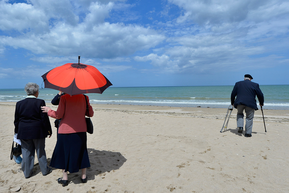 Relatives watch as D-Day veteran, Gordon Smith, 90, from Wiltshire, walks on Sword Beach at Hermanville-sur-Mer on the Normandy coast