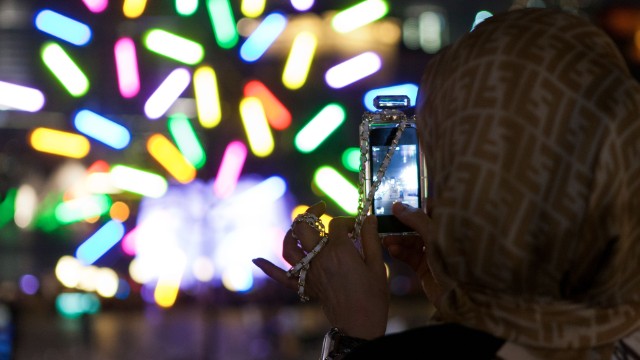 A spectator takes a photo of Big Tree, a light installation by architect Jacques Rival.