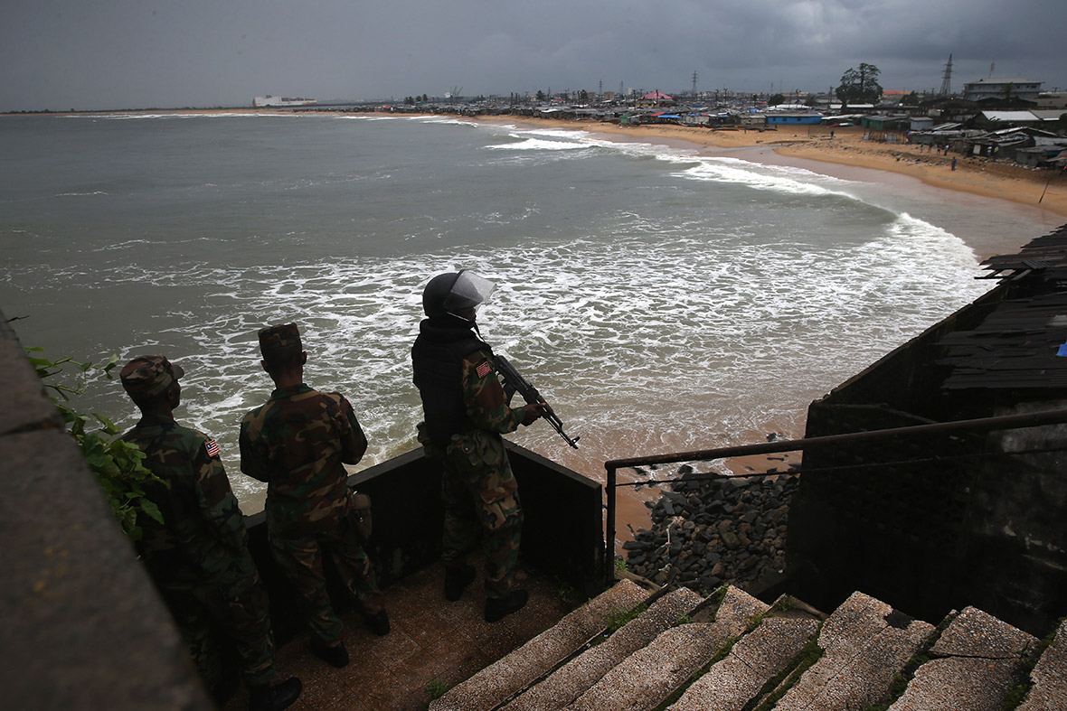Armed Liberian police officers look towards West Point on the second day of the Ebola quarantine on the seaside slum