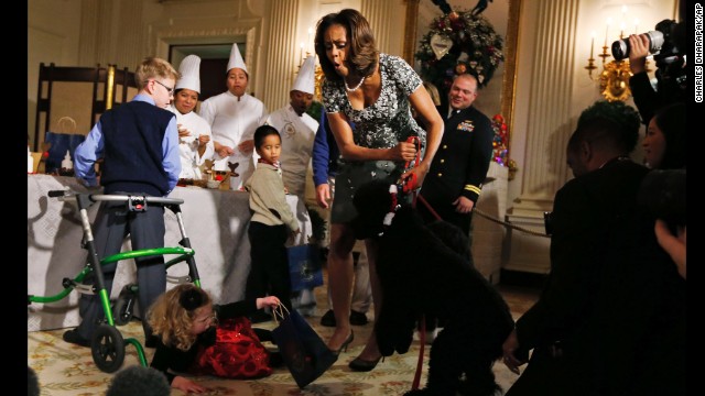 Michelle Obama reacts as Ashtyn Gardner, a 2-year-old from Mobile, Alabama, loses her balance while greeting Sunny, one of the Obamas' dogs, at a White House event in December.