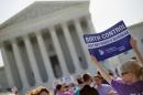 A demonstrator holds up a sign outside the Supreme Court in Washington, Monday, June 30, 2014. The Supreme Court is poised to deliver its verdict in a case that weighs the religious rights of employers and the right of women to the birth control of their choice. (AP Photo/Pablo Martinez Monsivais)