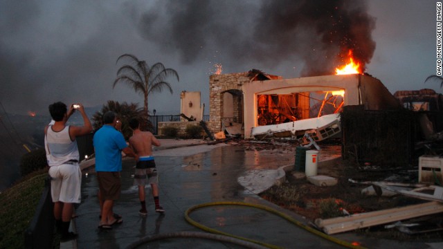 Residents photograph the burning ruins of their home that was destroyed in a wildfire in Carlsbad, California, on May 14. Drought conditions have fueled several wildfires across the state, fire officials said.