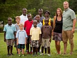 Mike and Hayley Jones, right travelled to Sierra Leone to adopt the eight children. Front row: Tucker, Zion, Judah Second row: Isaiah, Tyler, Malachi, Levi, Gabrielle Back row: Samuel and Michael