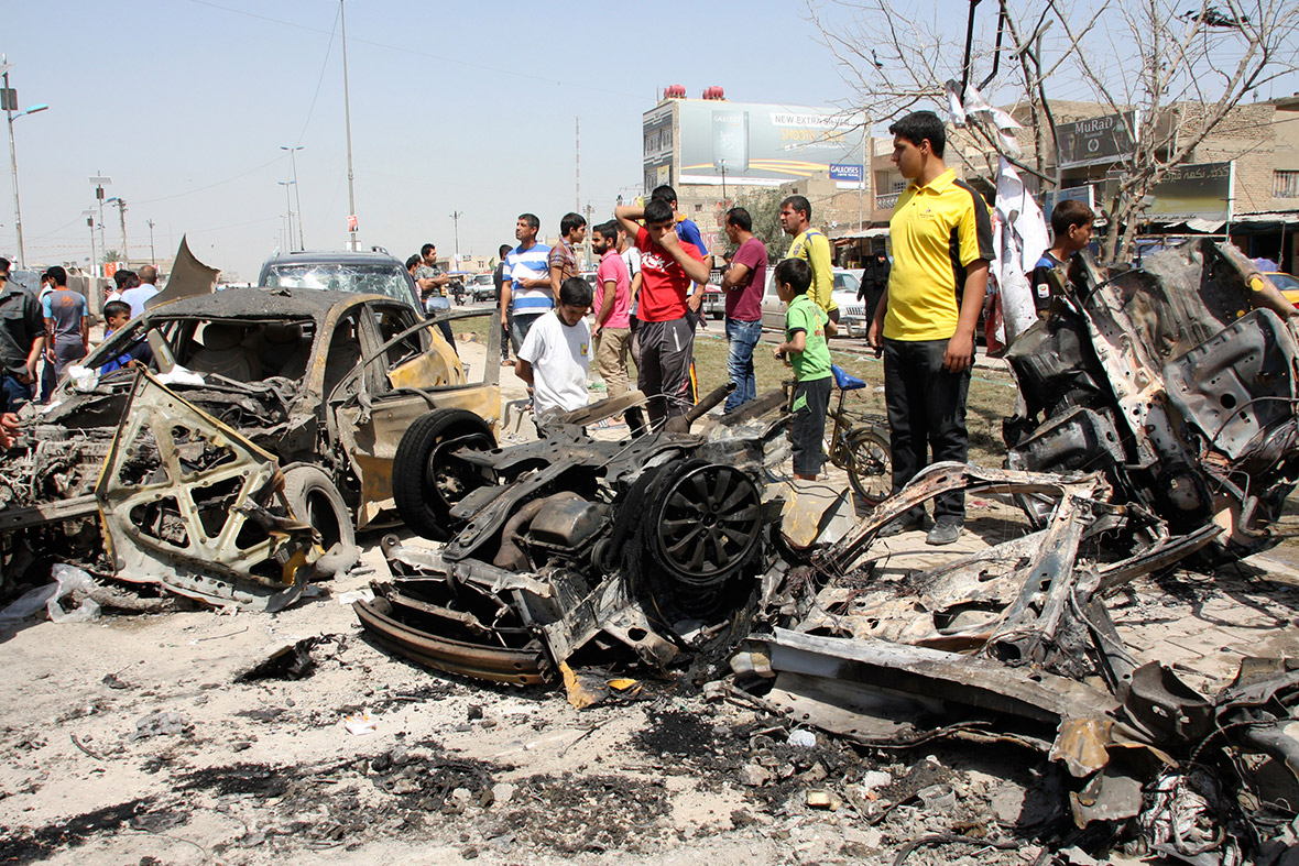 Residents look at wrecked cars at the site of a car bomb attack in Sadr City in Baghdad, which killed at least eight people and wounded over 40 others
