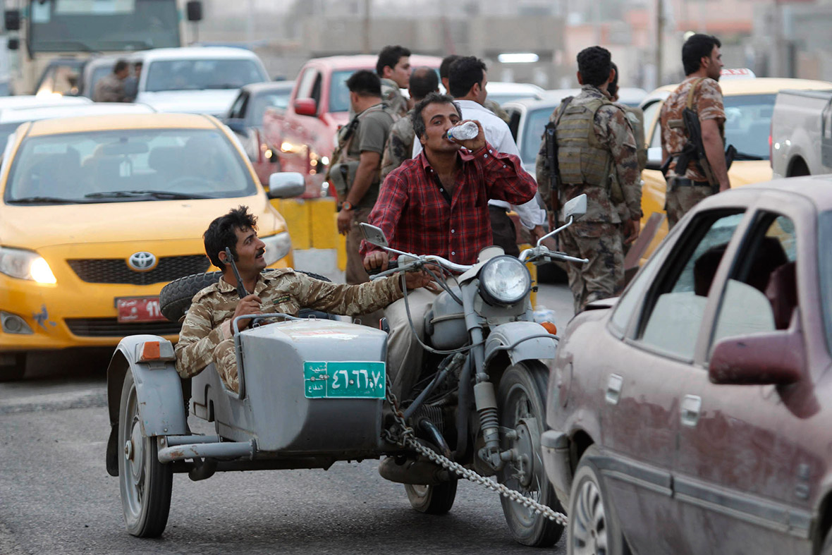 People ride a motorcycle that belonged to the Iraqi army, at a Kurdish military checkpoint on the outskirts of the northern Iraqi city of Kirkuk. Kurdish forces initially attempted to stop people driving vehicles looted from the Iraqi army at the checkpoint but eventually let them through as there were too many of them.