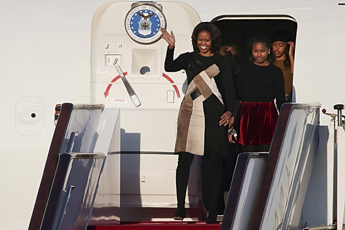 Michelle Obama waves as she walks out the plane with her daughters Sasha (2nd R) and Malia (R) upon their arrival at Beijing Capital International Airport in Beijing, March 20, 2014.