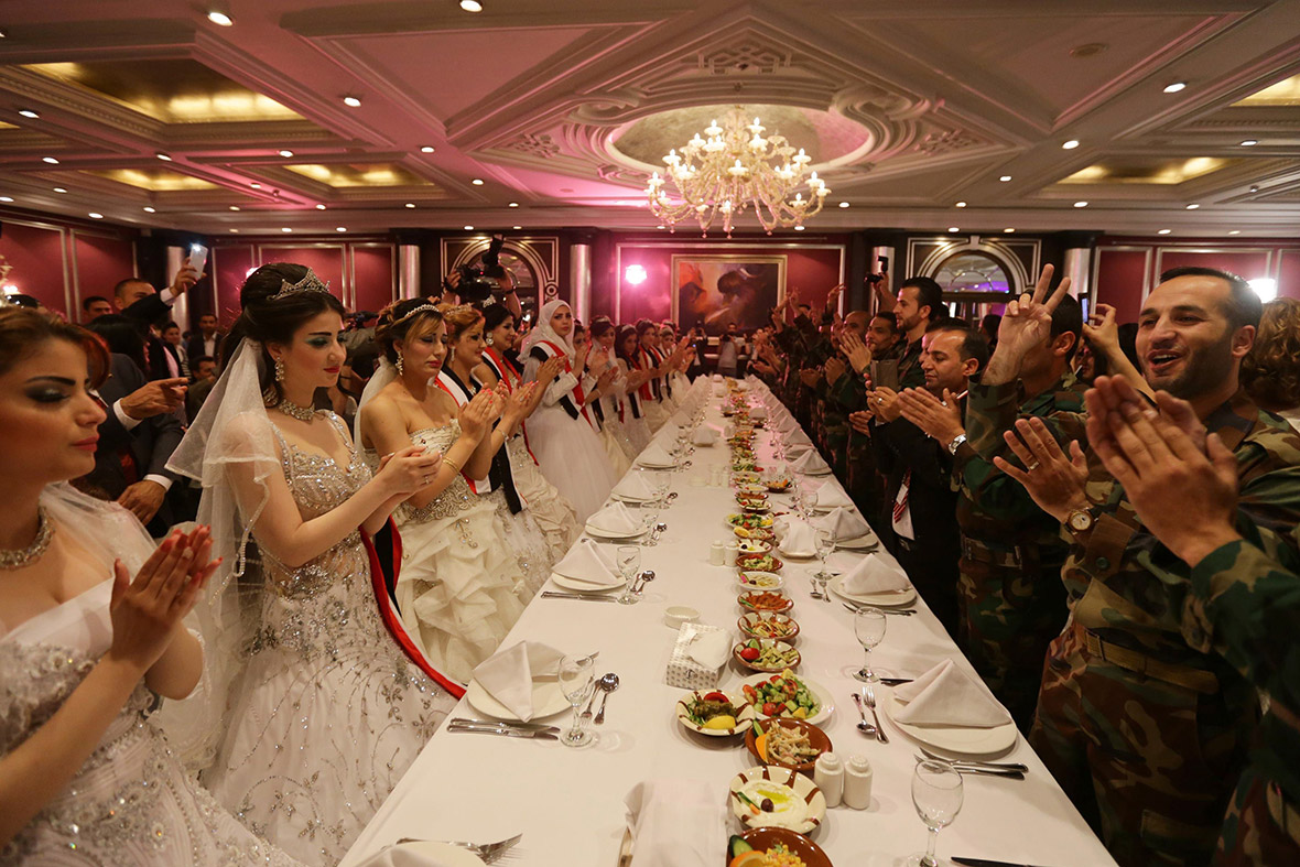 Twenty Syrian couples, made up of government soldiers and their brides, clap after their group wedding ceremony in Damascus