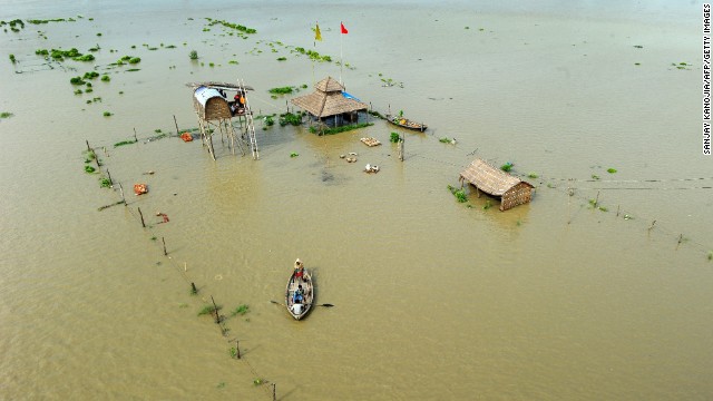 People flee submerged huts on the flooded banks of the Ganga river in Allahabad on Friday, August 8.