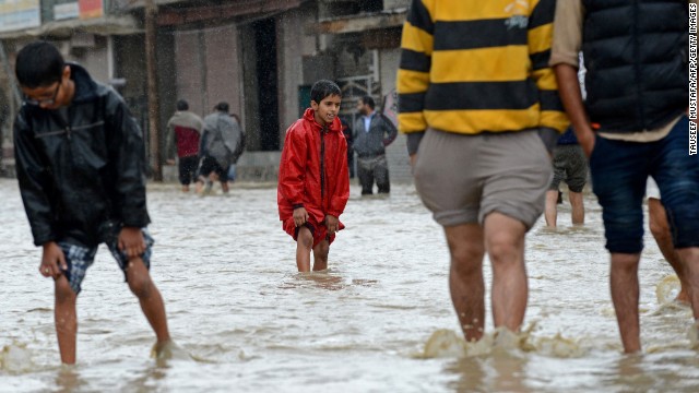 People wade through floodwaters on September 5 on the outskirts of Srinagar, India.