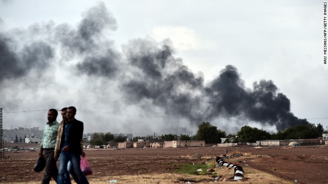 Kurdish men walk near the Turkish-Syrian border as smoke rises from the Syrian town of Kobani, as seen from the southeastern village of Mursitpinar, Turkey, on October 16. Civil war has destabilized Syria and created an opening for the ISIS militant group, which is also advancing in Iraq as it seeks to create an Islamic caliphate in the region.