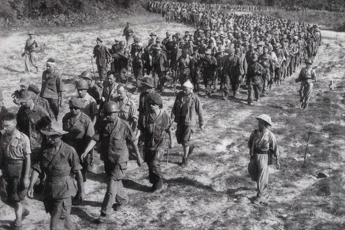 Captured French soldiers, escorted by Vietnamese troops, walk to a prisoner-of-war camp in Dien Bien Phu