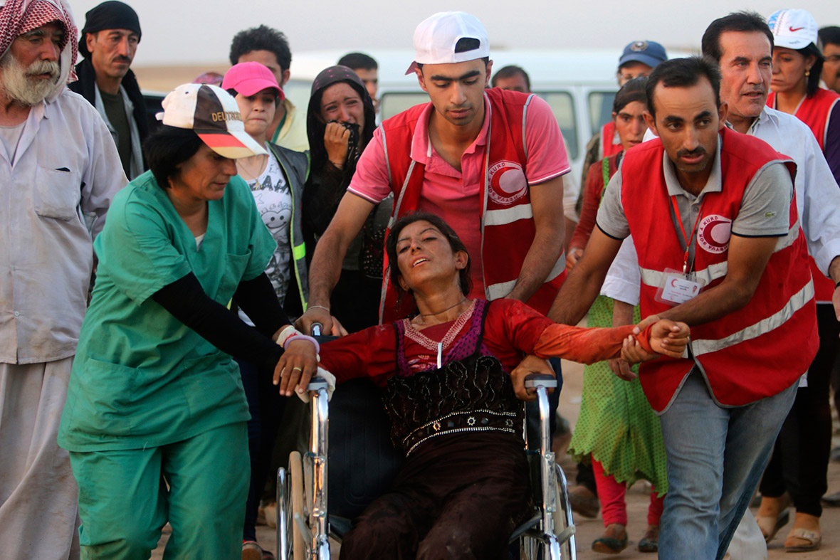 Members of the Kurdish Red Cresent help a woman in a wheelchair near the Syrian border town of Elierbeh.