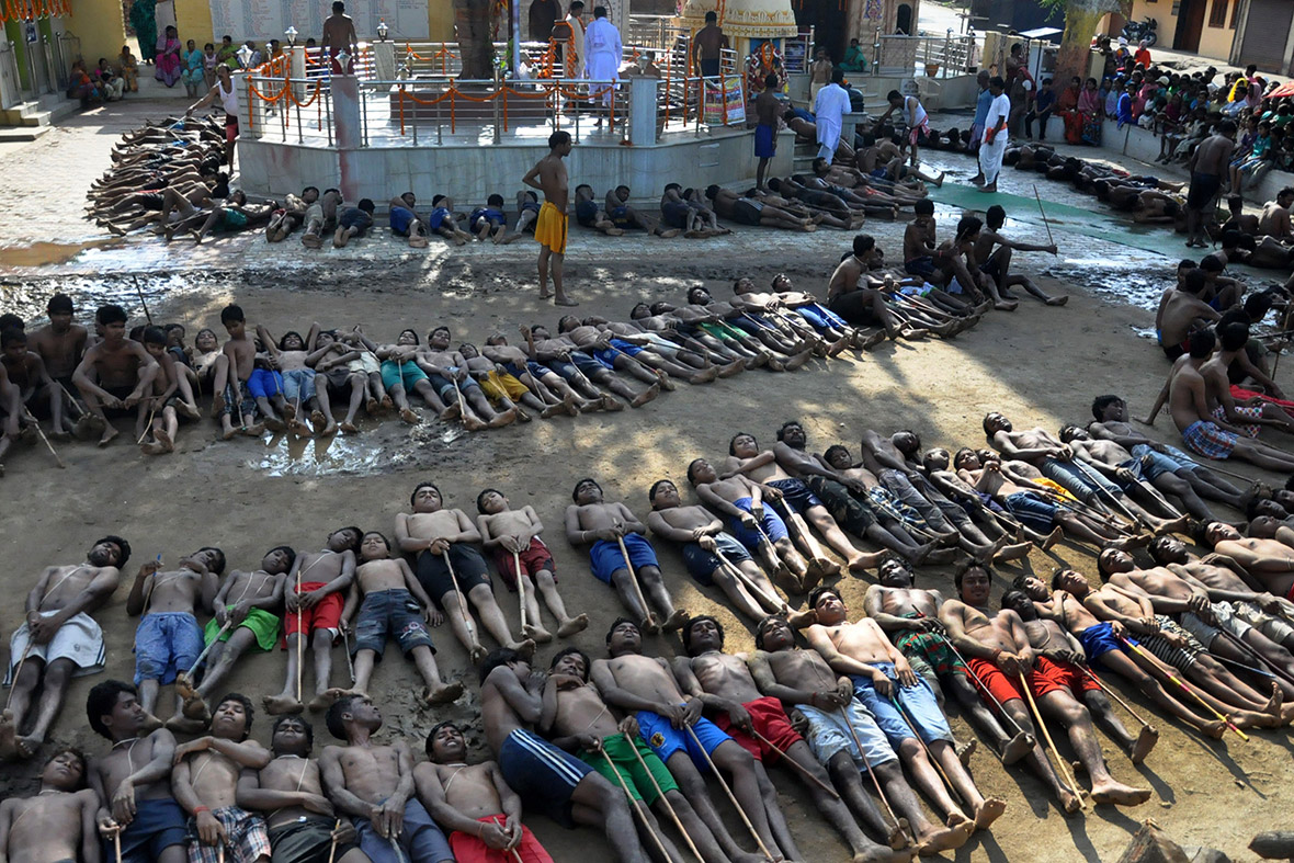 Farmers lie on the ground with sticks as they pray for rain during the Manda Festival at a temple on the outskirts of Ranchi, India