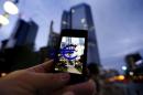 A passerby uses his smartphone to take a picture of the euro sign landmark in front of the headquarters of the European Central Bank (ECB) in Frankfurt