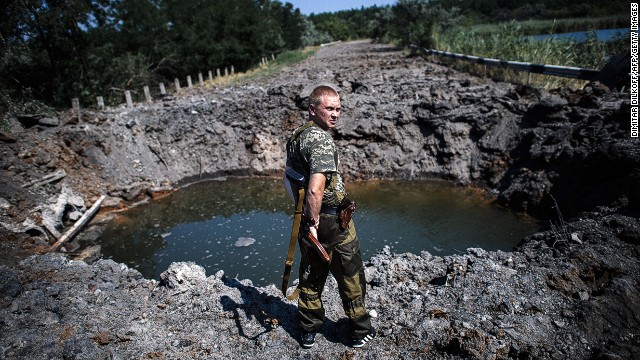 A pro-Russian gunman stands next to a bomb crater after shelling near Donetsk on Thursday.