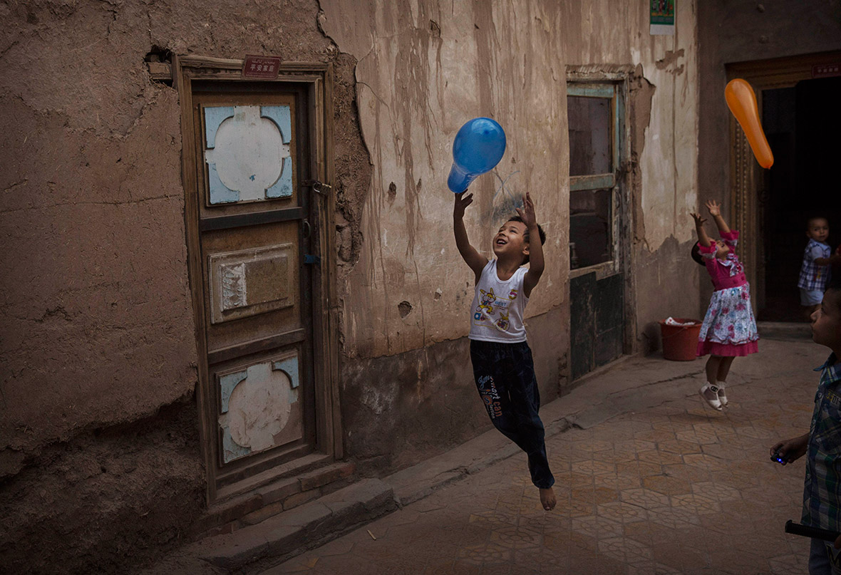 Uighur children play with balloons on the Eid holiday in an alleyway in Old Kashgar