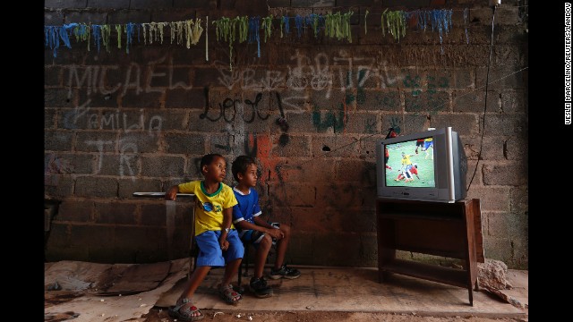 <strong>June 17:</strong> Boys at a slum on the outskirts of Brasilia, Brazil, watch a World Cup soccer match between Brazil and Mexico. Brazil hosted this year's World Cup, although <a href='http://ift.tt/1zAzbo8'>there were protests</a> over whether the money spent on the tournament would have been better used elsewhere.