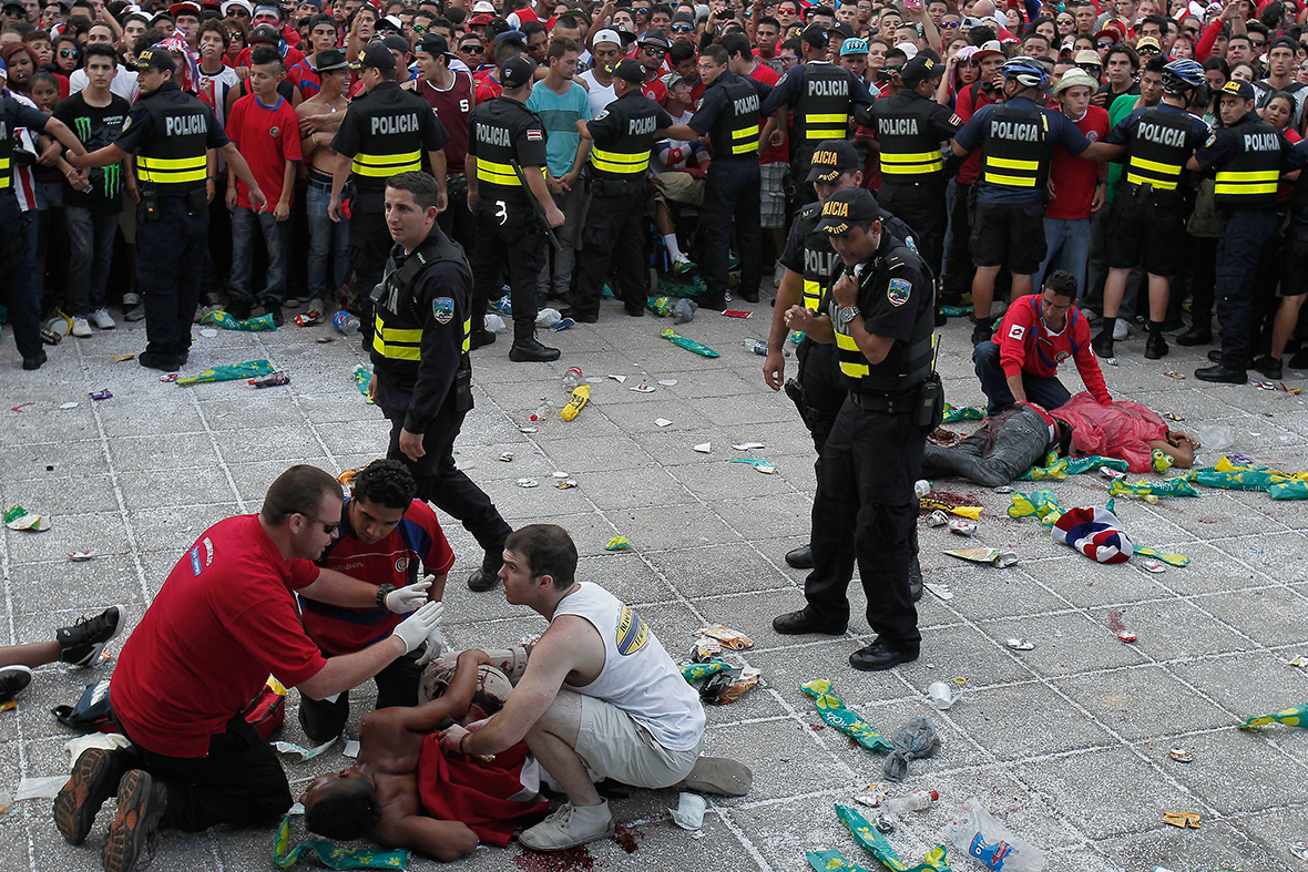 Police officers hold back fans after several men were stabbed while watching a public screening of the 2014 Brazil World Cup quarter-final game between Costa Rica and the Netherlands, in San Jose, Costa Rica