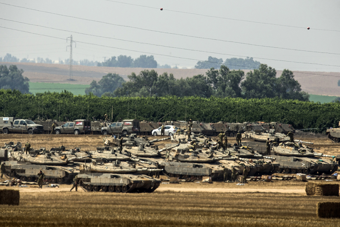 Israeli soldiers stand next to tanks positioned on the Israeli side of the border with the Gaza Strip