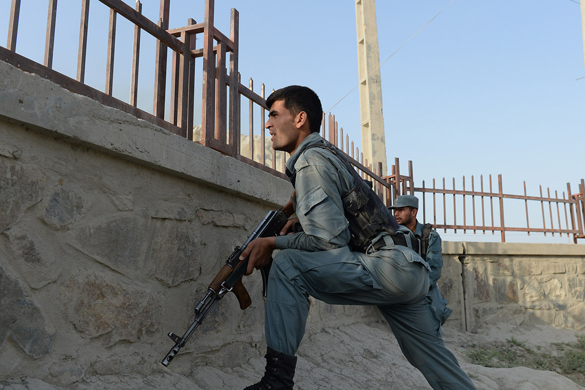 Afghan police take cover near the site of a suicide attack in front of Kabul's airport
