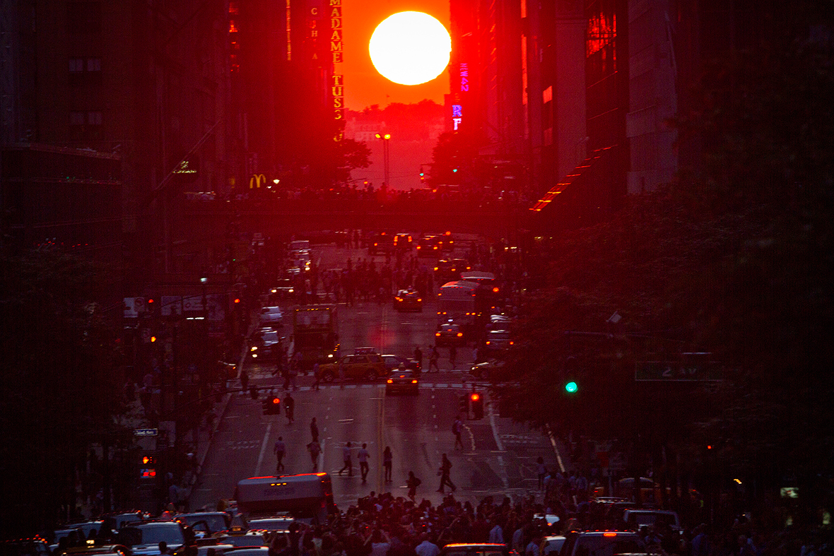 People crowd onto 42nd Street as they take photos of the 'Manhattanhenge' phenomenon, occurring twice a year, when the setting sun aligns itself with the east-west grid of streets in Manhattan.