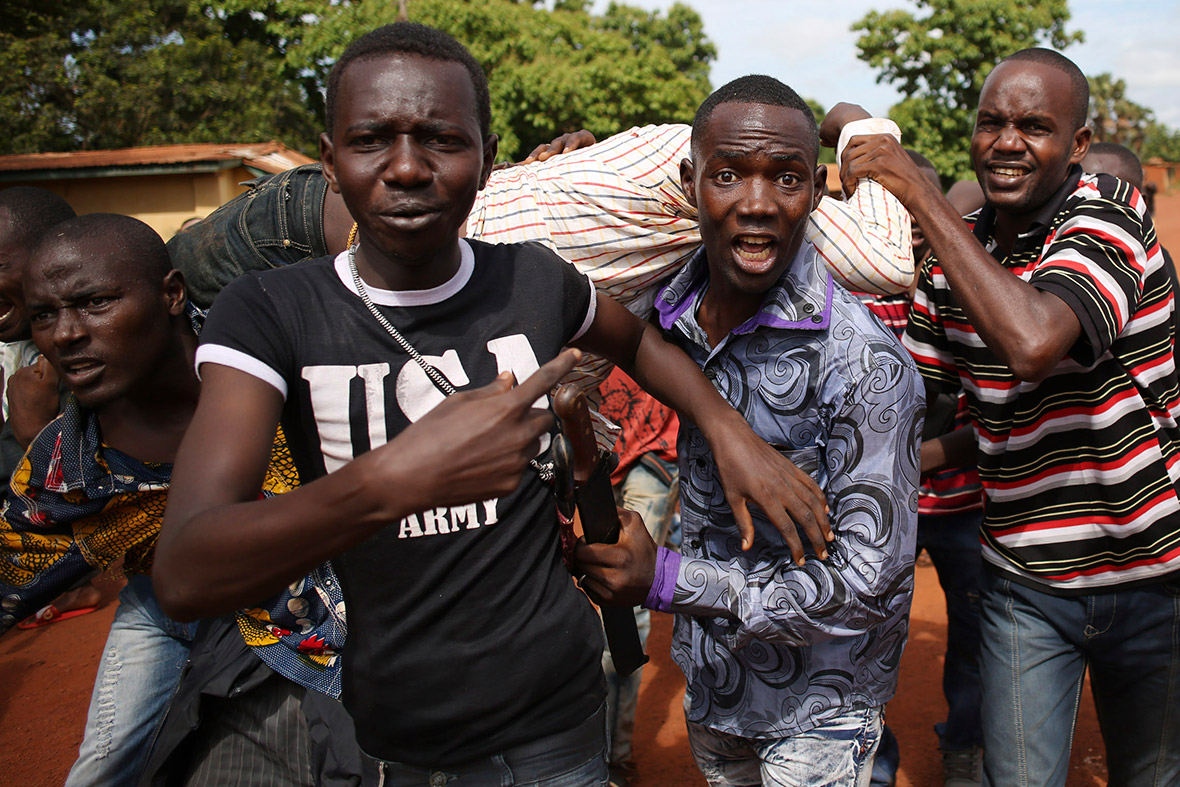 Protesters carry a man who was shot after French troops opened fire at protesters blocking a road in Bambari