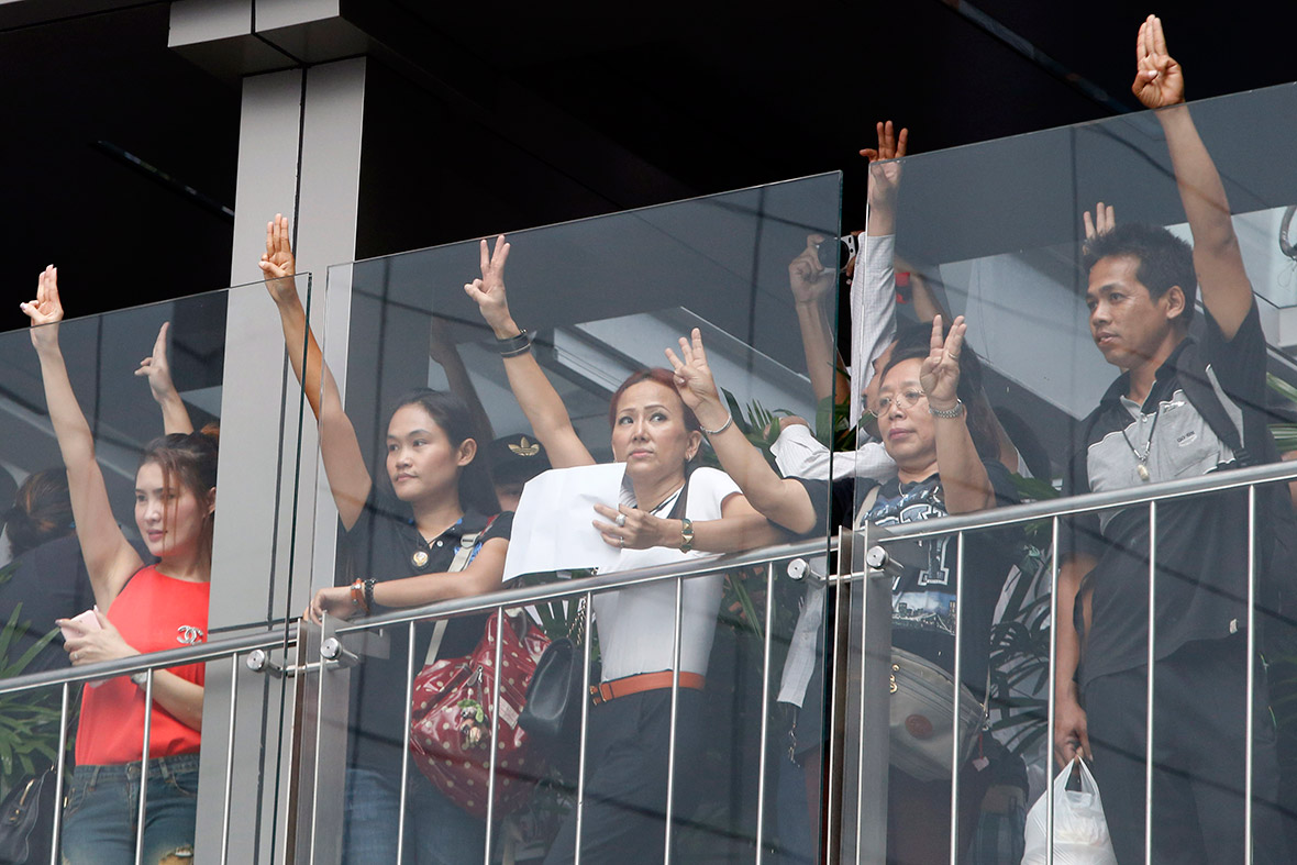 Protesters in a Bangkok shopping centre hold up their three middle fingers in the air