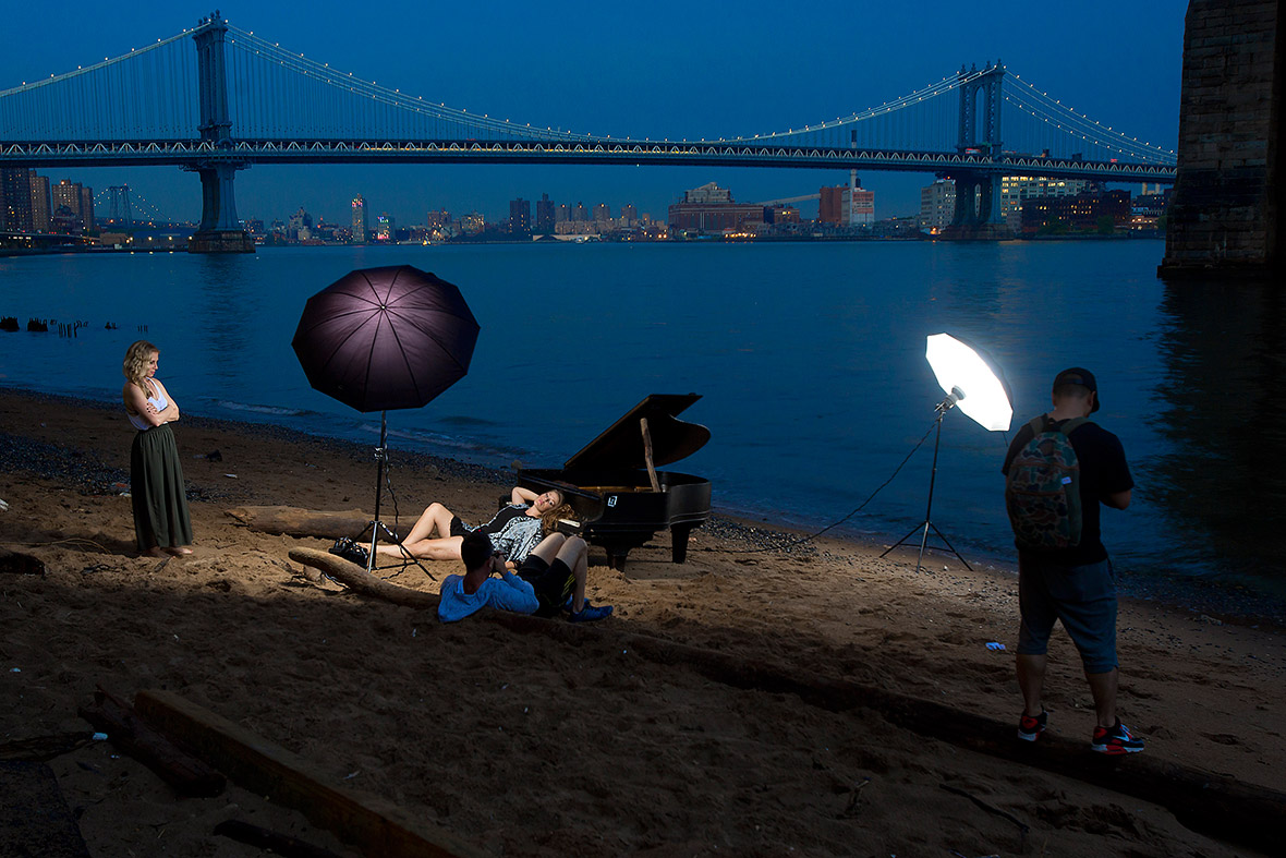 A woman poses for a photo on a grand piano that has been left beside the East River, during a fashion shoot underneath the Brooklyn Bridge in New York. The piano has been there for about a week, puzzling locals as to how it got there
