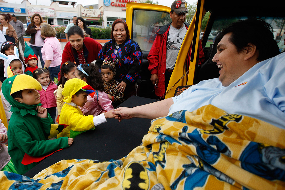 March 20, 2009: Manuel Uribe shakes hands with children wearing Spring costumes as he takes a trip around town on a modified truck