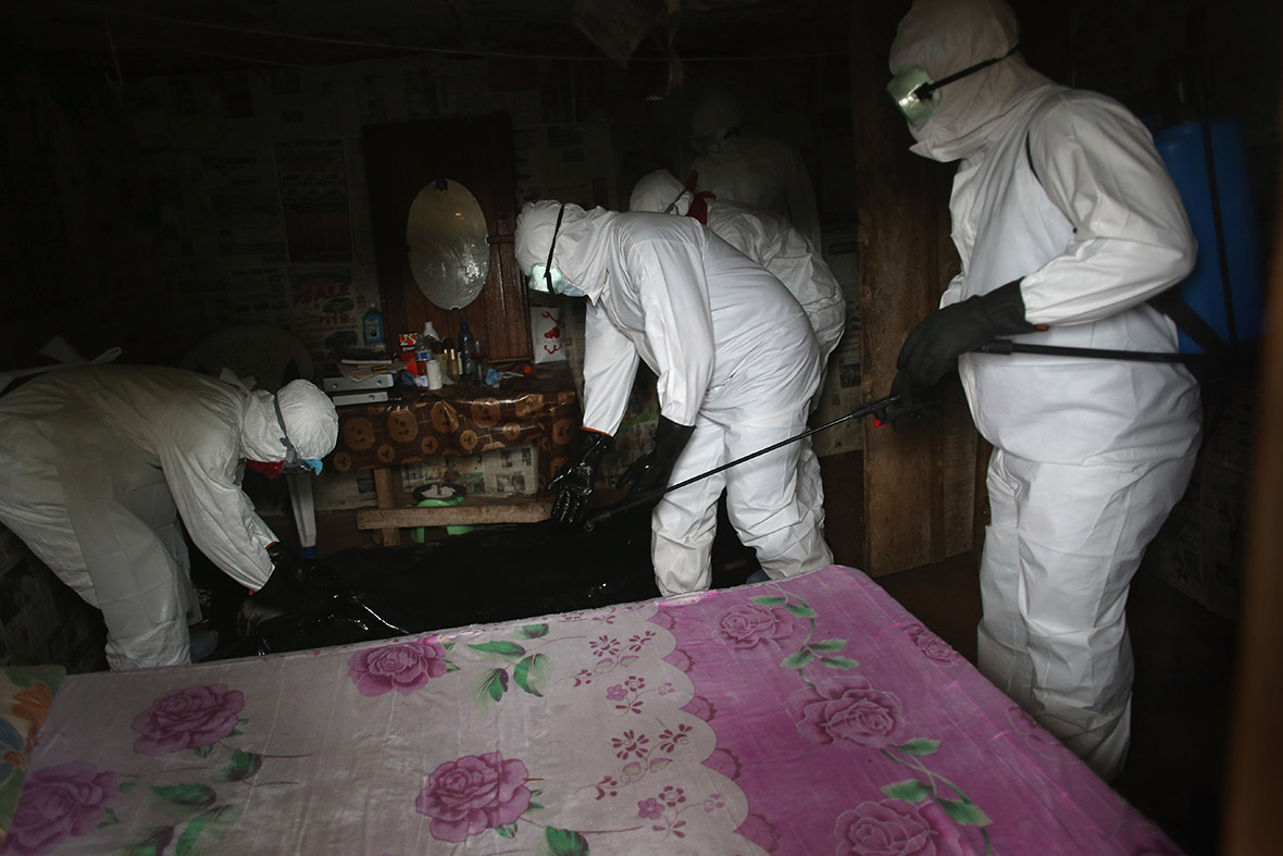 A Liberian burial team wearing protective clothing retrieves the body of a 60-year-old Ebola victim in his home near Monrovia