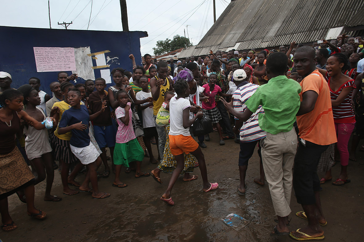 A family (with their backs to the camera) leaves an Ebola isolation centre after a mob forced open the gates