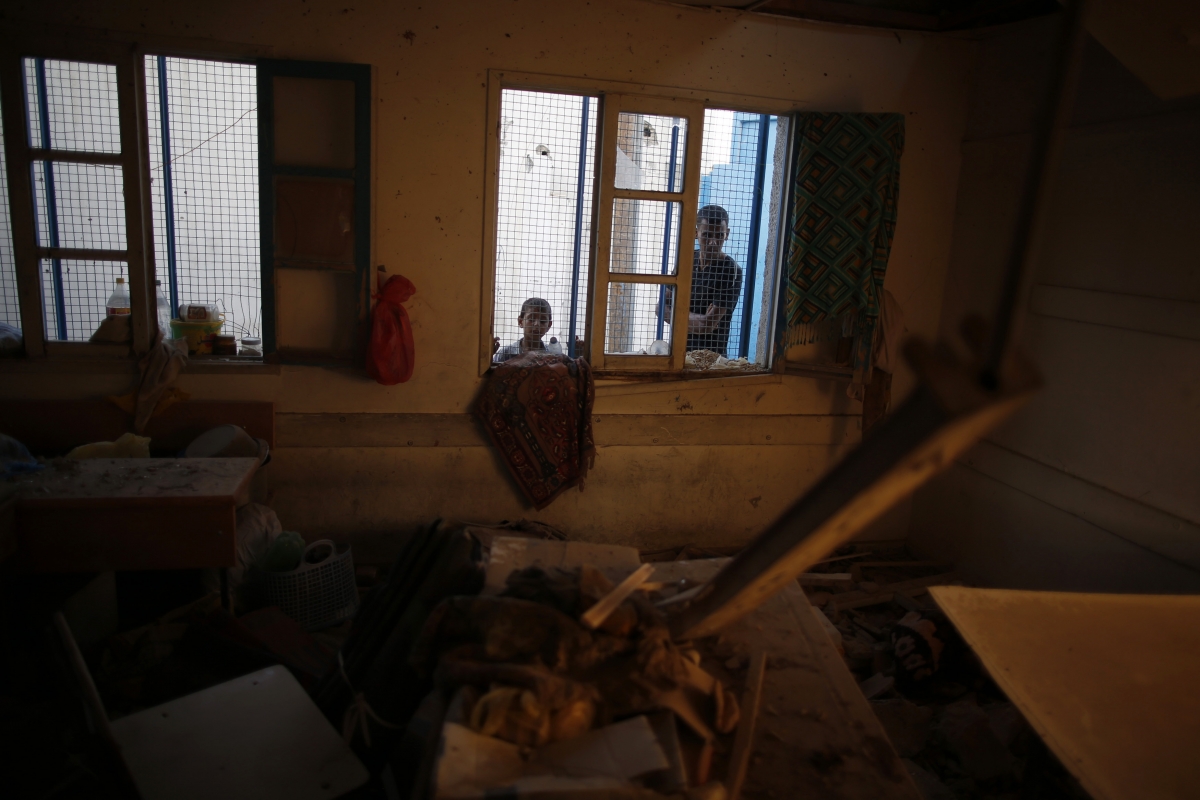 Palestinians look at a damaged classroom in a United Nation-run school sheltering Palestinians displaced by an Israeli ground offensive, that witnesses said was hit by Israeli shelling