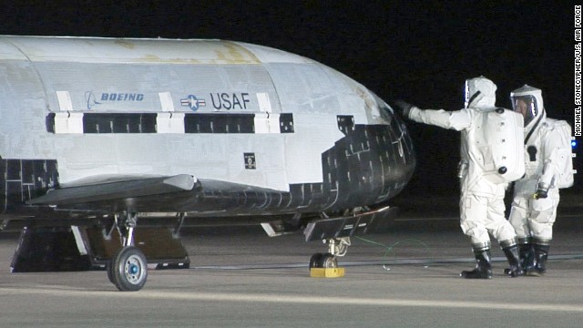 Technicians in self-contained atmospheric protective ensemble suits conduct initial checks on the X-37B after its landing on December 3, 2010.